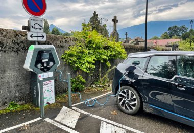 Menthon Saint Bernard, Fransa - 10 Eylül 2021: Bir Fransız caddesindeki elektrikli bir arabayı halka açık bir şarj noktasına bağlayan bir tel var.