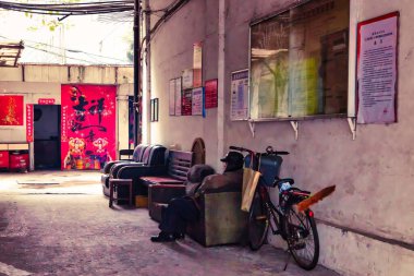 Chengdu, Çin - 28 Kasım 2009: Yaşlı bir vatandaş Çin 'de küçük bir sokakta bir kanepede dinleniyor.