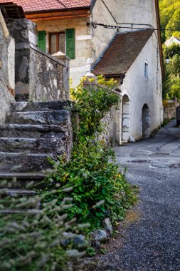 Menthon Aziz Bernard, Fransa - 10 Eylül 2020: Taşlı tarihi bir Fransız köyü manzarası, pencerelerin önündeki kepenkler ve yuvarlak kapılı kemerler