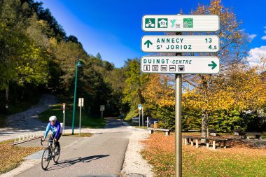 Duingt, France - October 22 2021 : a road sign along the bicycle trail along the lake indicates directions to different destinations clipart