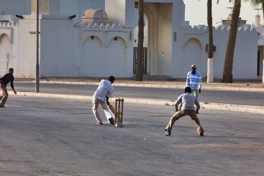 Doha, Katar - 26 Ocak 2010: Cuma namazında işçiler izinli ve sokakta bekliyorlar veya kriket oynuyorlar