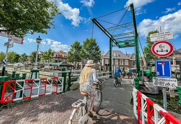 stock image Leidschendam, Netherlands - 24 August 2021: cyclists are passing over an historic dutch draw bridge in a small historic village