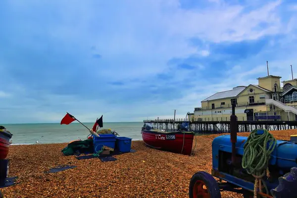 bognor regis, united kingdom - March 04 2022: a fishing boat is laying on the beach with boxes with nets and gear and a tractor