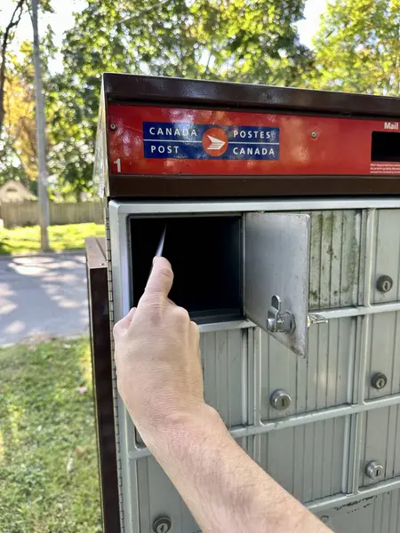 stock image port perry, canada - september 19 2023: a person is opening a letter box in a communal canada post mailbox