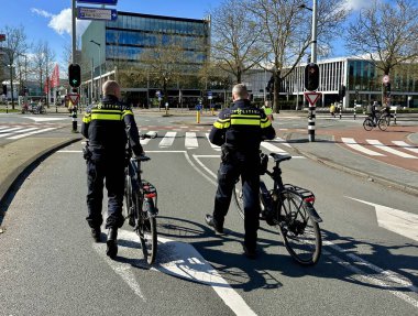 Amsterdam, Hollanda - 7 Nisan 2024: Hollanda Ulusal Polisi bisikletlerinin yanında bisiklet kaskıyla yürüyor