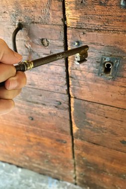 Menthon saint Bernard, France - October 23 2021: a person is seen opening an historic wooden door with a vintage medieval metal key