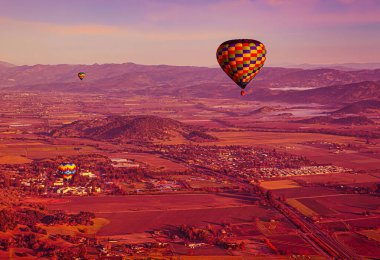 Napa, United States - February 17 2013 : a hot air balloon ing ride over the valley and moutains of a wine region with panoramic scenery clipart