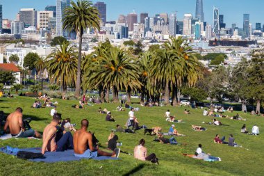 San Francisco, ABD - 10 Şubat 2020: hipster ve belki de milenyum, San Francisco manzaralı Dolores Park 'ta yarı çıplak oturuyorlar.