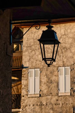 Talloires, France - September 08 2020 : a lantern is hanging in silhouette in an old medieval small french town clipart