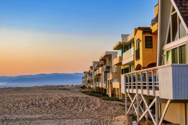Oxnard, ABD - 21 Şubat 2020: Renkli ahşap kiralama mülkleri plajda dizilmiş, cennet gibi bir gün batımıyla