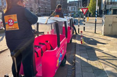 Den Haag, Hollanda - 28 Ekim 2021: Çocuk esirgeme kurumları tarafından kullanılan elektrikli arabayla iki kişi