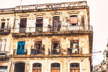 Havana, Küba - Temmuz 06 2018: Sokağın köşesindeki bu sömürge döneminden kalma binaların bakımı için para yok. Pencereden sarkan insanlar