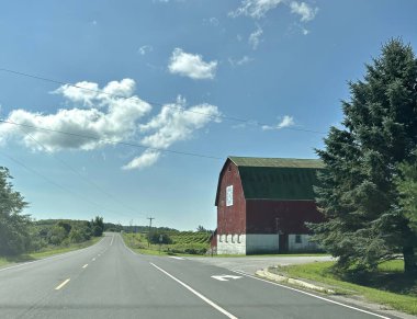 Cobourg, Kanada - 16 Ağustos 2023: Kanada kırsal yolu boyunca kırmızı ahşap görünümlü nostaljik bir vintage ahır duruyor.