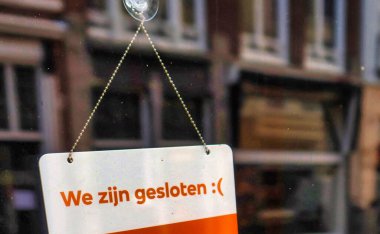 Lahey, Hollanda - 03 Ocak 2022: Hollandalı dilinde kapalı olduğumuza dair bir işaret bir dükkan veya restoranın giriş kapısına yapıştırılmıştır.