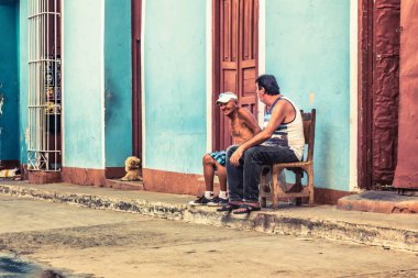 Trinidad, Küba - 15 Temmuz 2018: 18. yüzyılda kalan eski bir İspanyol sömürge kasabası. Yaşlı adamlar dışarıda koltuklarda oturup konuşuyorlar..