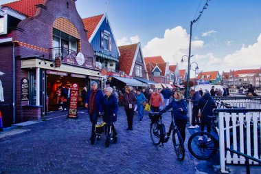 Volendam, Hollanda - 08 Ekim 2022: Hollanda köyünün önünde hediyelik eşya dükkanları ve teraslarıyla yürüyen insanlar