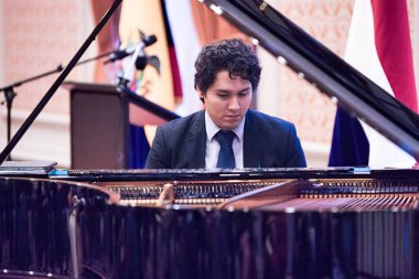 the hague, netherlands - 20 September 2022: a pianist is sitting behind the grand piano during a concert performance clipart