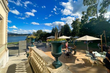 geneva, switzerland - 08 September 2022: a terrace in a small park at the waterfront of the lake leman and people sitting on a terrace
