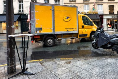 Paris, Fransa - 11 Nisan 2023: Yağmurlu bir Paris caddesinde paket dolu Fransız posta kamyonu