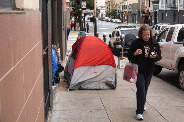 San Francisco, United States - February 13 2020 : a homeless person lives in a tent in the middle of the sidewalk downtown san francisco