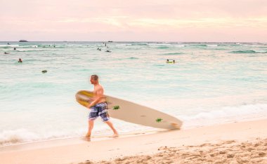 Honolulu, ABD, 06 Aralık 2012: Sörf tahtası ile sörf yapan bir sörfçü Waikiki 'de bir cankurtaran direğini pasif hale getiriyor.