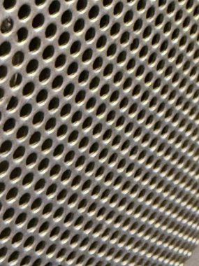 Eşit aralıklarla aralıklı deliklerin oluşturduğu ve benzersiz dokusunu ve endüstriyel tasarımını sergileyen bir metal ağın yakın görüntüsü.