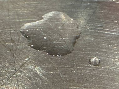 Kalp şeklinde bir damlacık metalik bir yüzeye dayanır ve maddenin yansımasını ve dokusunu belirtir. Işık ilginç bir etki yaratır..