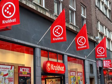 Hollanda, den haag - 18 Ekim 2024: Den Haag 'daki Kruidvat mağazasının önünde dairesel bir logo ile süslenmiş kırmızı bayraklar.