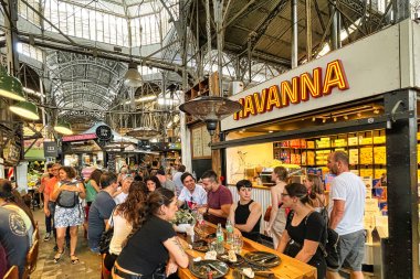 buenos aires, argentina - 29 October 2022 : people visiting and eating at the big and famous San Telmo food market within an historic building with steel glass roof clipart