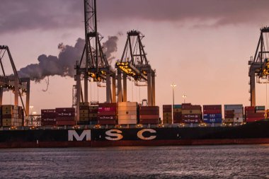 Rotterdam, Netherlands - November 22 2021 : lines of huge half and completely automated cranes to offload containers from deck ship clipart