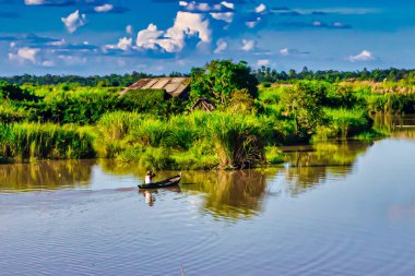Bago, Myanmar - 02 Aralık 2012: Geleneksel Myanmar bambu kırsal evi ya da kırsal kesimde nehir ve uzun kuyruklu teknelerin bulunduğu cambaz ayaklıkları üzerindeki kulübe