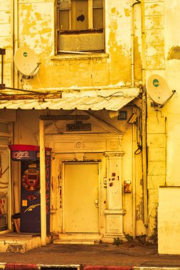 Tel Aviv, İsrail - 11 Kasım 2010: Tel Aviv caddesinde terk edilmiş bir koloni evinin önünden geçenler