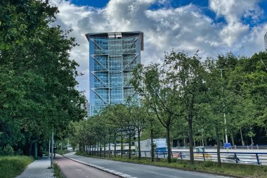 den haag, netherlands - may 30 2022: the malietoren is a modern skyscraper of metal and grass with a highway going under neath