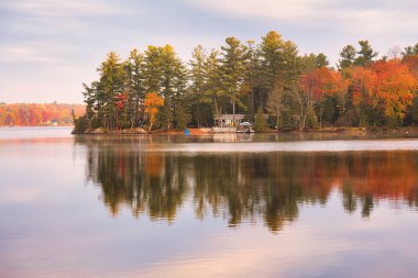 kawartha lakes, canada - 20 October 2022: a cabin on the shore of a small lake in the kawartha lakes region in fall colors