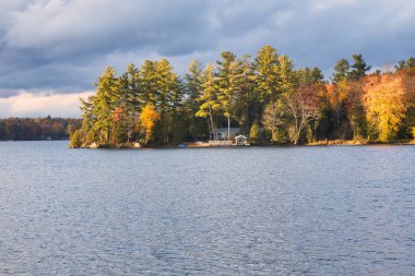 kawartha lakes, canada - 20 October 2022: a cabin on the shore of a small lake in the kawartha lakes region in fall colors