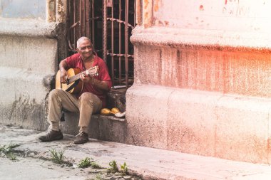 Havana, Küba - Temmuz 08 2018: Havana sokaklarında gitar çalan bir adam sıcak bir öğleden sonra yerel kültür ve müzik sergilemekten zevk alıyor.