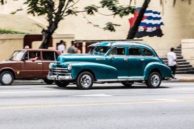 Havana, Küba - Temmuz 06 2018: Havana 'da güneşli bir günde Küba' nın eşsiz otomotiv kültürünü sergileyen tarihi binaların yanından geçen antika arabalar.