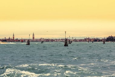 Venedik, İtalya - 16 Şubat 2016: Güneş Venedik gölünün üzerinde batarken sakin atmosferdeki uzak işaretleri vurgulayan dalgalar hafifçe dalgalanır.