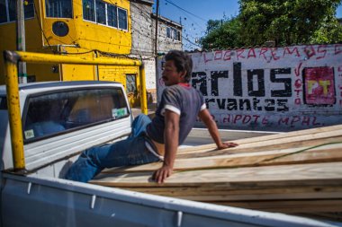 Mexico City, Mexico - 27 Nisan 2010: Bir adam gün boyunca Meksika 'nın canlı caddelerinde ilerlerken bir kamyonun arkasındaki tahta panellerde oturuyor.
