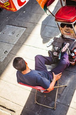 Mexico City, Mexico - Mai 01 2010: Bir adam Meksika 'nın kalabalık bir caddesinde güneşin tadını çıkaran bir sandalyede oturur..