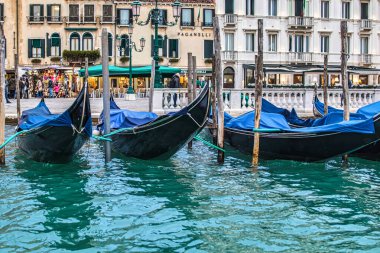 Venedik, İtalya - 16 Şubat 2016: Venedik 'in berrak sularında tarihi binalarla çevrili bir gecede mavi kapaklı Gondollar bir rıhtıma bağlandı.