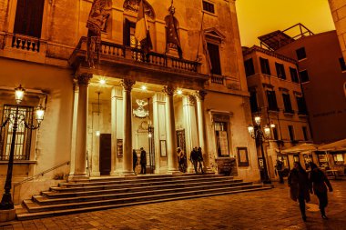 Venedik, İtalya - 16 Şubat 2016: Venedik 'teki tarihi bir tiyatronun önünde sıcak ışıklar alacakaranlık sırasında büyük girişi aydınlatırken insanlar toplandı.