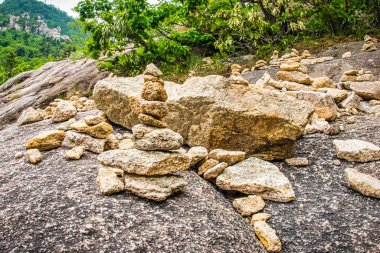 Sokcho, Güney Kore - 8 Haziran 2015: Güney Kore 'de yeşilliklerle çevrili doğal kaya oluşumları ve gün ışığında kayalık bir arazinin yanında istiflenmiş taşlar.