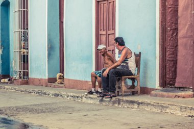 Trinidad, Küba - 15 Temmuz 2018: Trinidad Küba 'da iki yaşlı adam güneşli bir günde evlerinin önünde otururken sohbet ediyorlar.