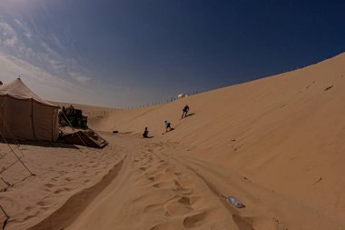 Doha, Katar - 28 Ocak 2010: Ziyaretçiler sıcak bir öğleden sonra Doha Çölü 'nde kum tepelerinde kum kayağı yapmaktan keyif alıyorlar.