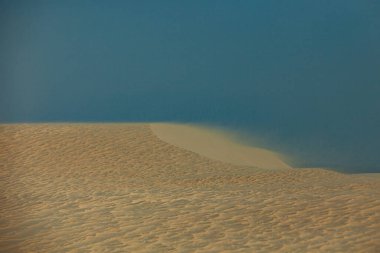 Doha, Katar - 28 Ocak 2010: Sade mavi sulara doğru altın kum tepeleri günbatımında Doha Katar 'ın benzersiz manzarasını sergiliyor.