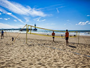 Den Haag, Hollanda - Haziran 2009: İnsanlar açık bir günde hague rıhtımının yanındaki plajda voleybol oynuyorlar. Dalgalar arkadaki mavi gökyüzünün altında görünür..