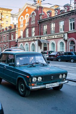 Moskova, Rusya - 10 Eylül 2010: Klasik bir mavi araba Moskova 'da tarihi binalar ve gün ışığında park edilmiş araçlarla çevrili bir caddede geziniyor.
