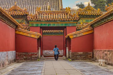 Pekin, Çin - 19 Temmuz 2010: Pekin 'de geleneksel avlu mimarisini keşfeden kişi gün batımında canlı kırmızı duvarlar ve karmaşık çatılarla çevrili.