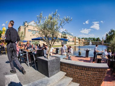 Den Haag, Hollanda - 30 Mayıs 2009: İnsanlar Hollanda 'da gündüz vakti bir göletin yakınındaki açık bir kafede dinleniyor ve yemek yiyorlar.